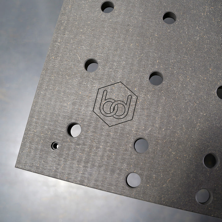 Benchdogs MFT Black Valchromat with multiple holes and a logo embossed on it, on a reflective surface.