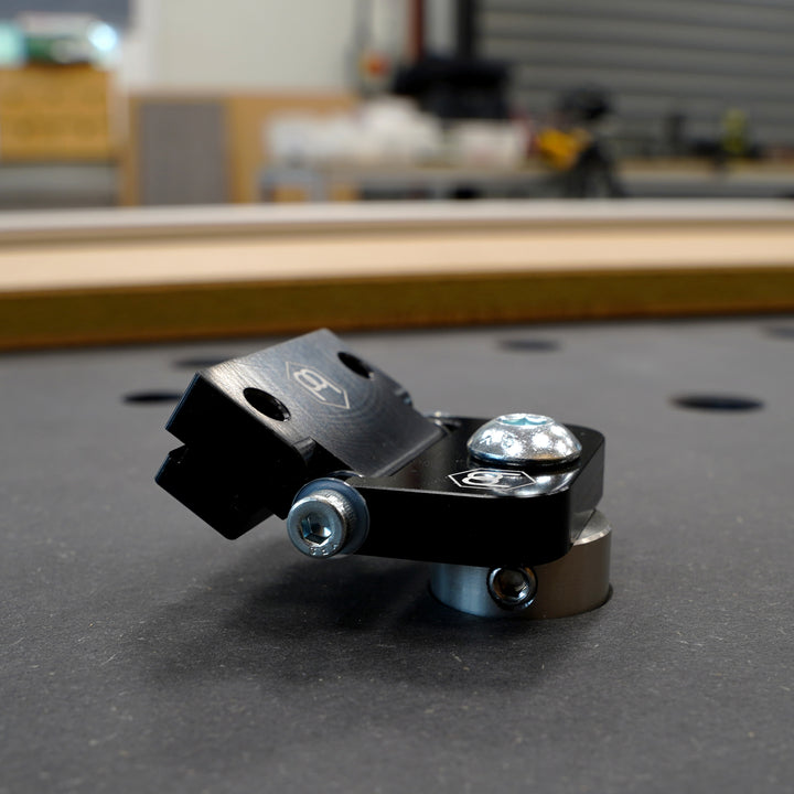 Close-up of a Hinge Dog on a grey surface with a blurred workshop background